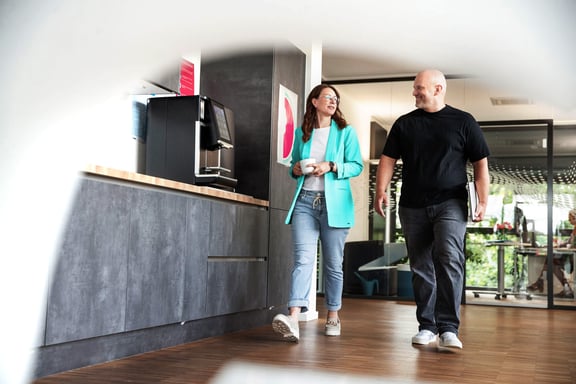 Mitarbeitende besprechen sich an der Kaffeemaschine